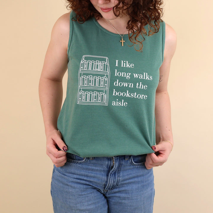 Woman wearing a green tank top with text that reads 'I like long walks down the bookstore aisle' and bookshelf graphic on a beige background.