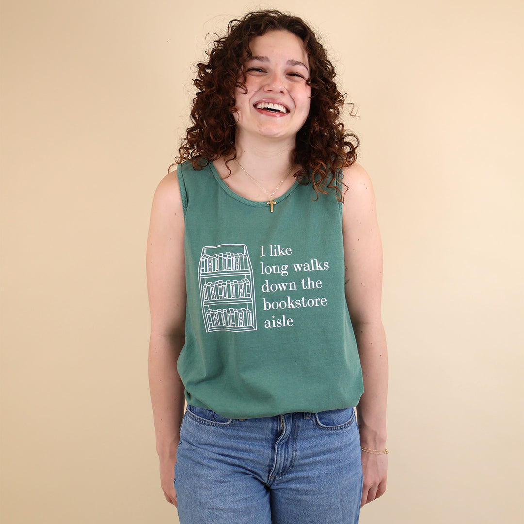 Woman wearing a green tank top with text that reads 'I like long walks down the bookstore aisle' and bookshelf graphic on a beige background.