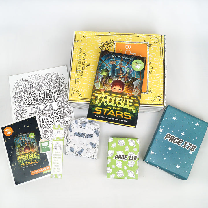 a hardcover edition of Trouble in the Stars sits on a yellow box. In front of the box (from left to right) are a book flyer, coloring page, book sticker, bookmark, a white drawstring bag, a green box with spaceships on it, and a blue box with white stars on it. The boxes and bags all have page numbers.