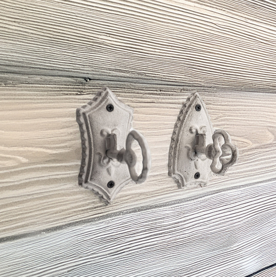 Two gray key hooks against a gray wood wall.