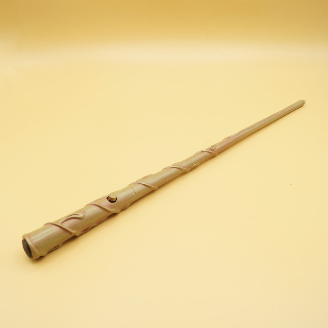A yellow background. A magic wand points away from the viewer showing the detailing on the handle and the button to make it light up.