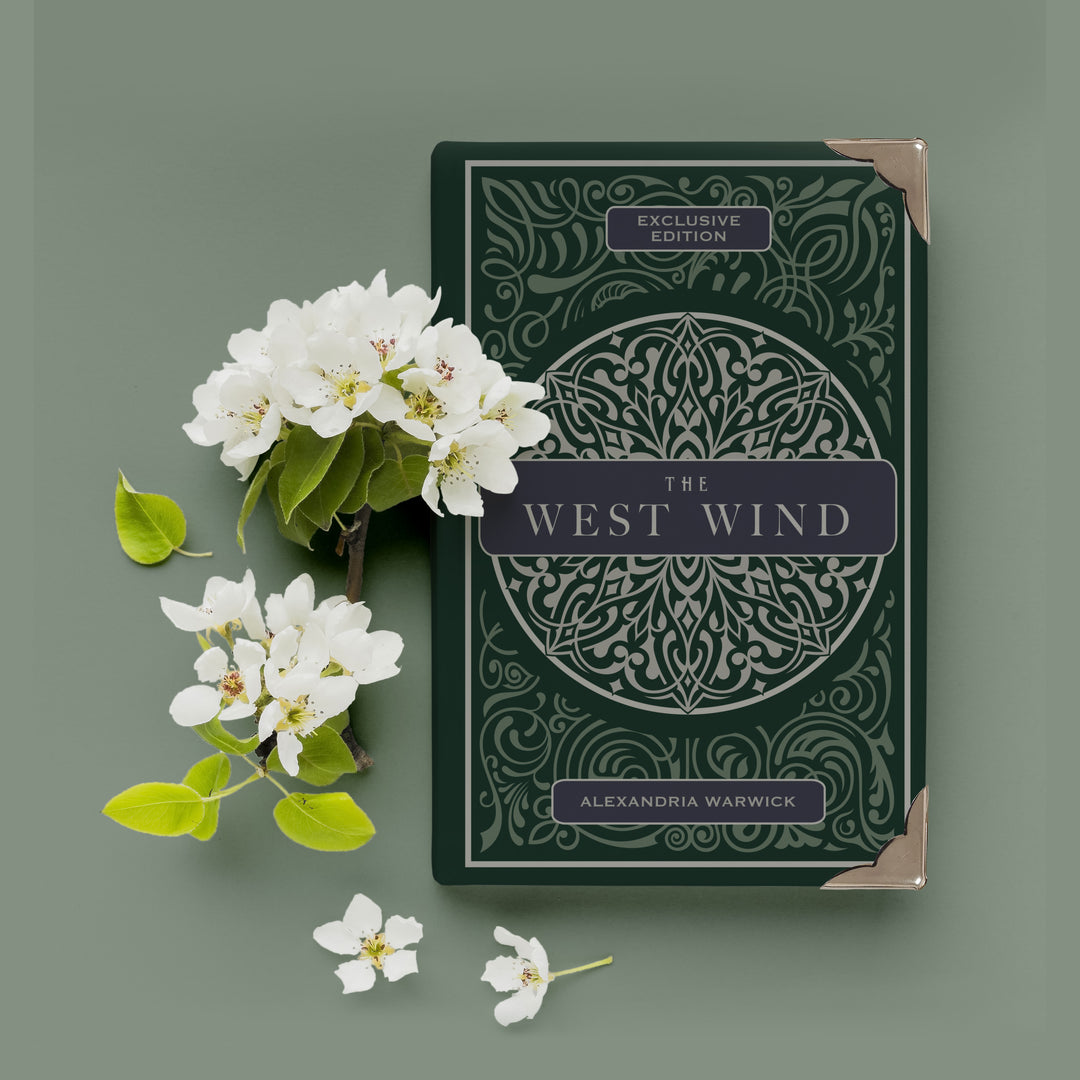 a dark green hardcover special edition of The West Wind with metal corners sits next to white flowers