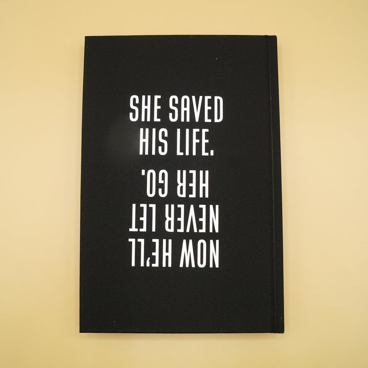 the back hardcase of a hardcover custom edition of What Remains. features the quote "She saved his life. Now he'll never let her go" in white writing over a black background