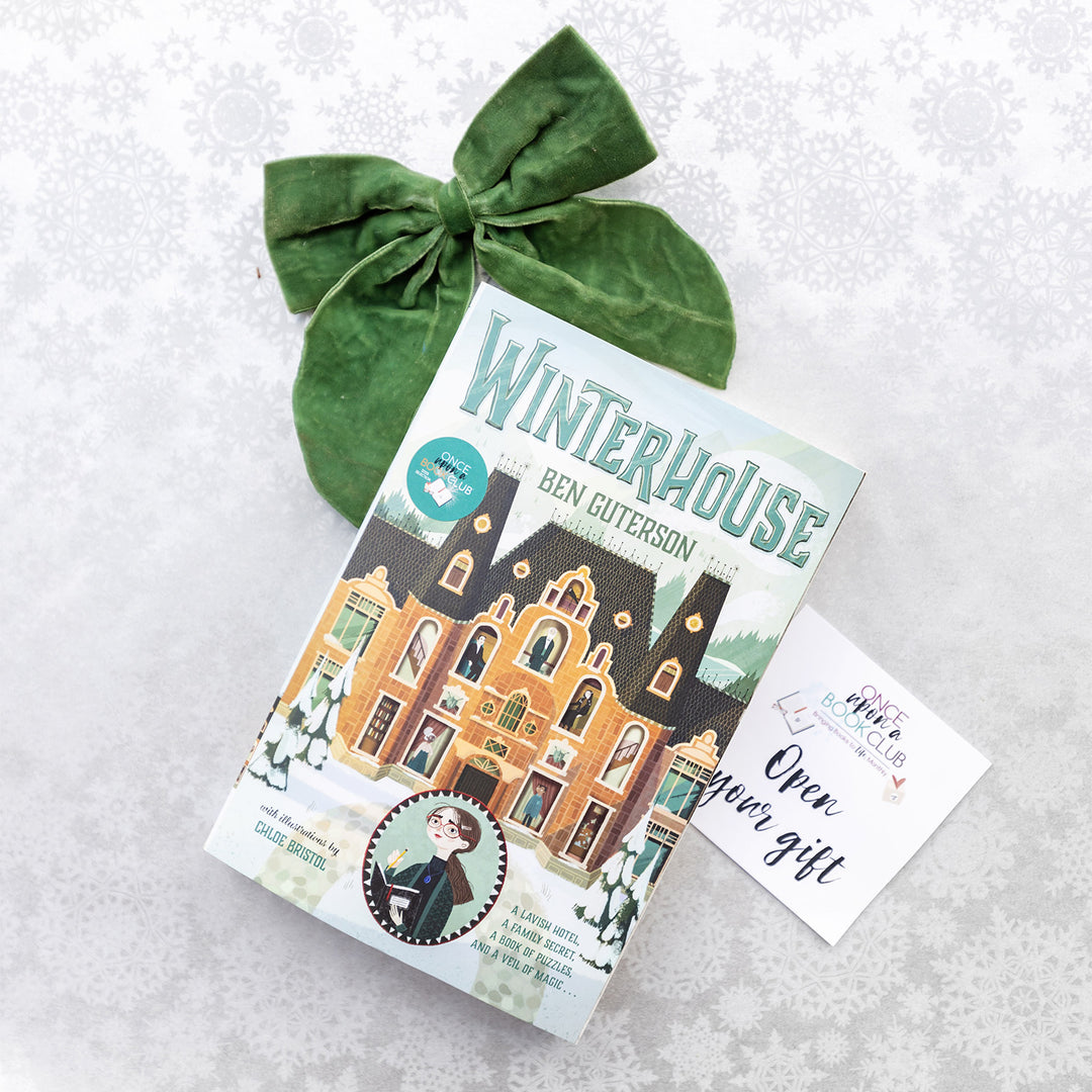 A new paperback copy of Winterhouse by Ben Guterson with a green bow on a snowflake-patterned background.