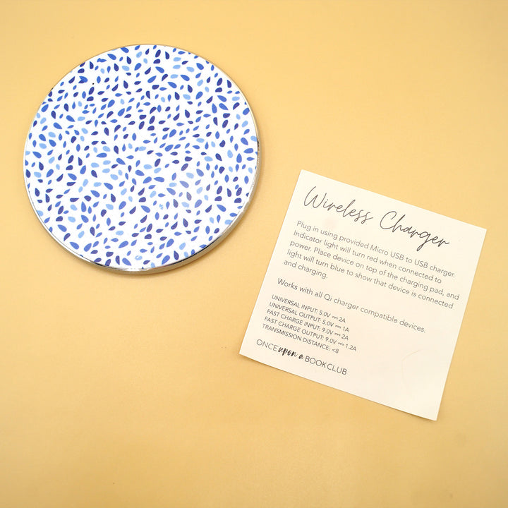 a white wireless phone charger with blue dots on it is next to a piece of paper labeled Wireless Charger