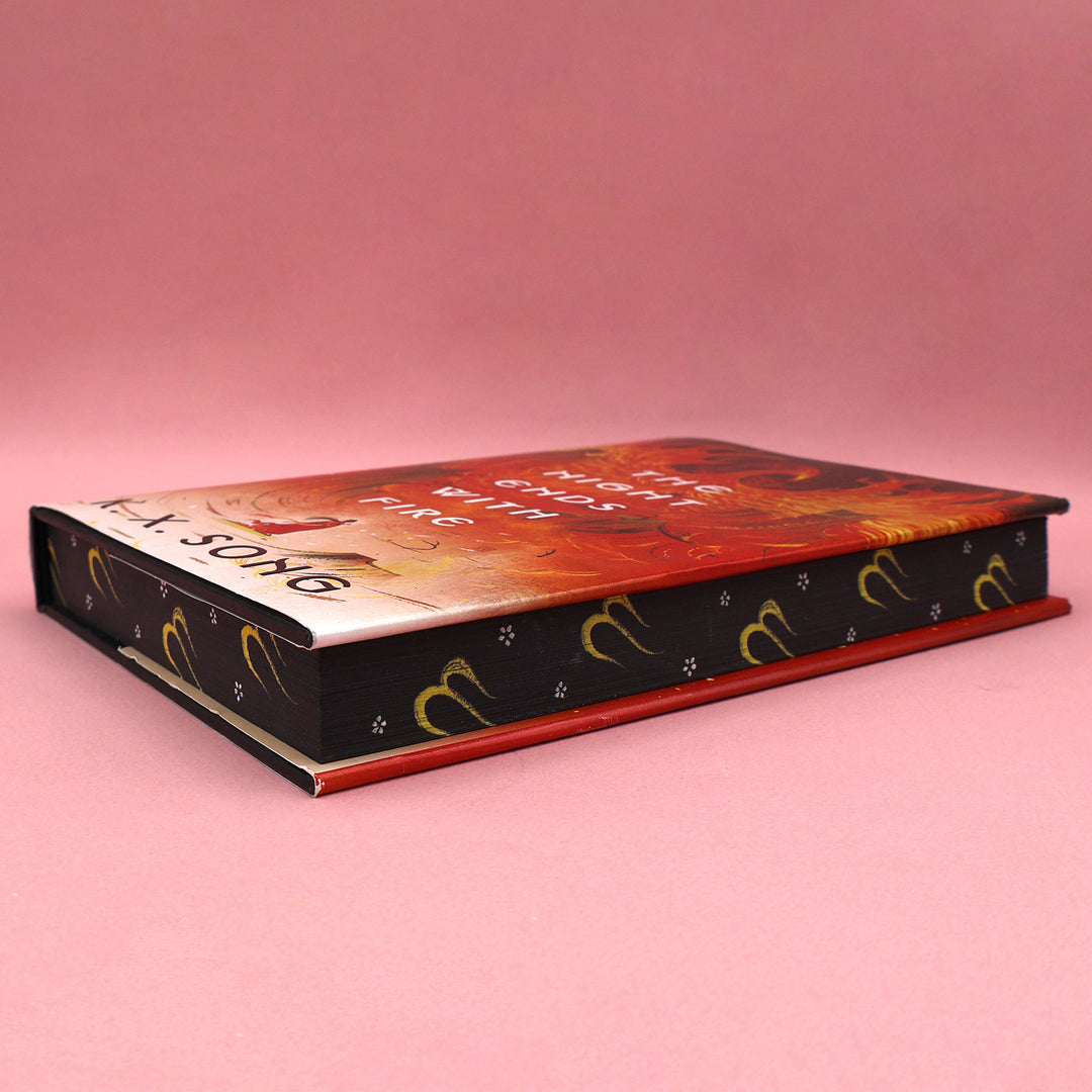 Book edges of 'The Night Ends with Fire' by K.X. Song on a pink background