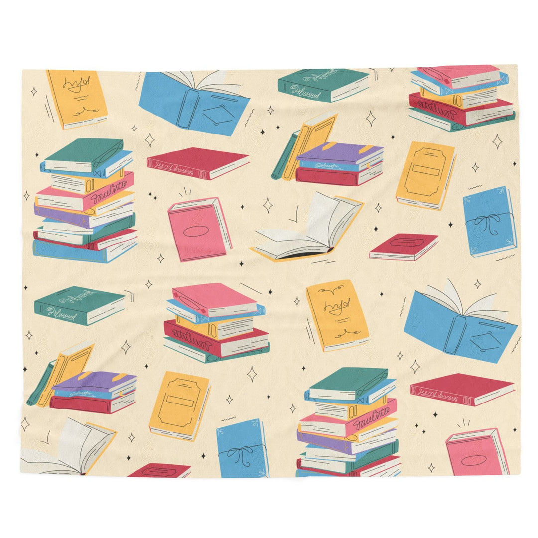 A blanket featuring colorful books on a creamy butter yellow background. The blanket is spread on a white background.