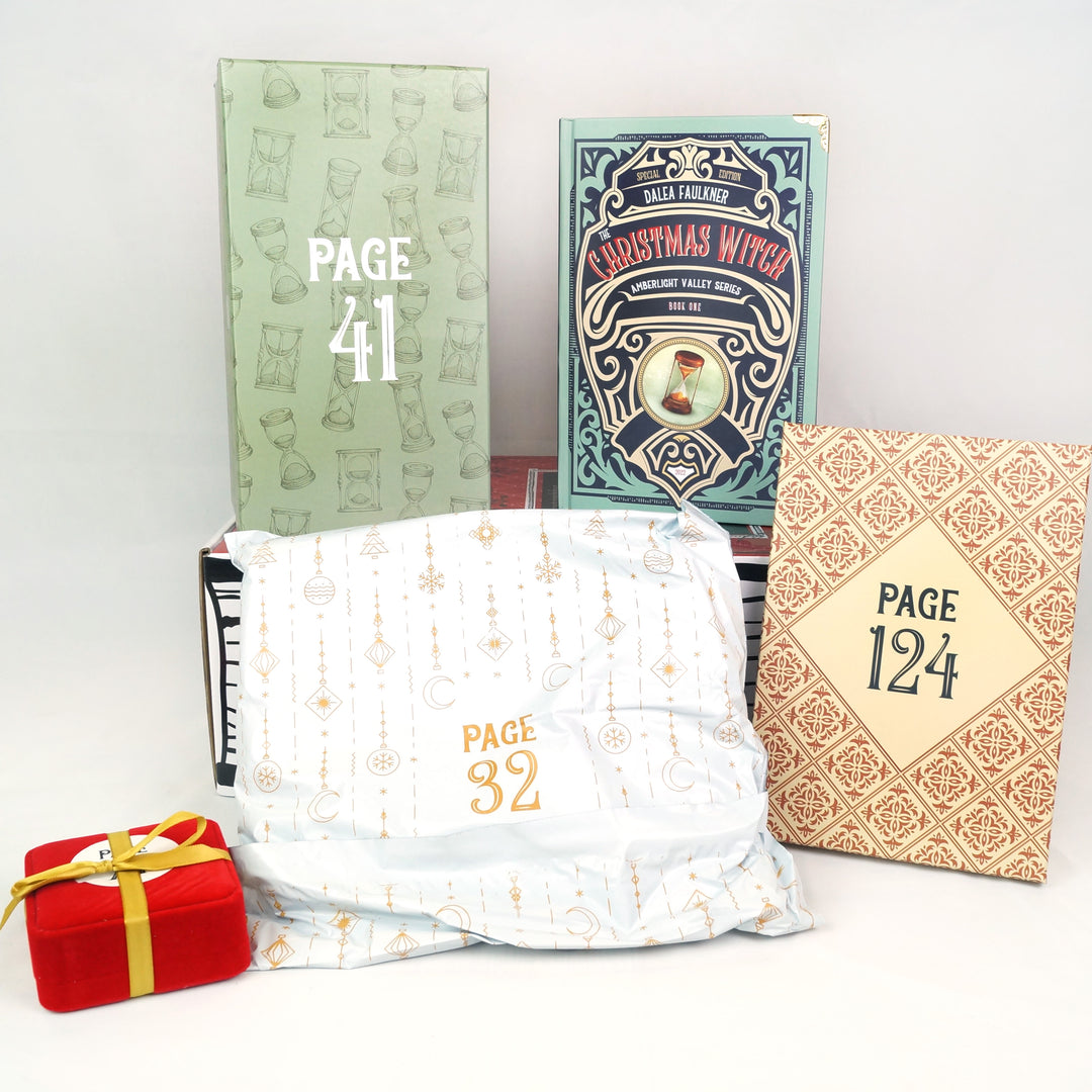 A hardcover special edition of The Christmas Witch and a green box with hourglasses on it stand on a red Once Upon a Book Club box. In front are a red square box with yellow ribbon, white polybag, and beige box. The boxes and bag are all labeled with page numbers.