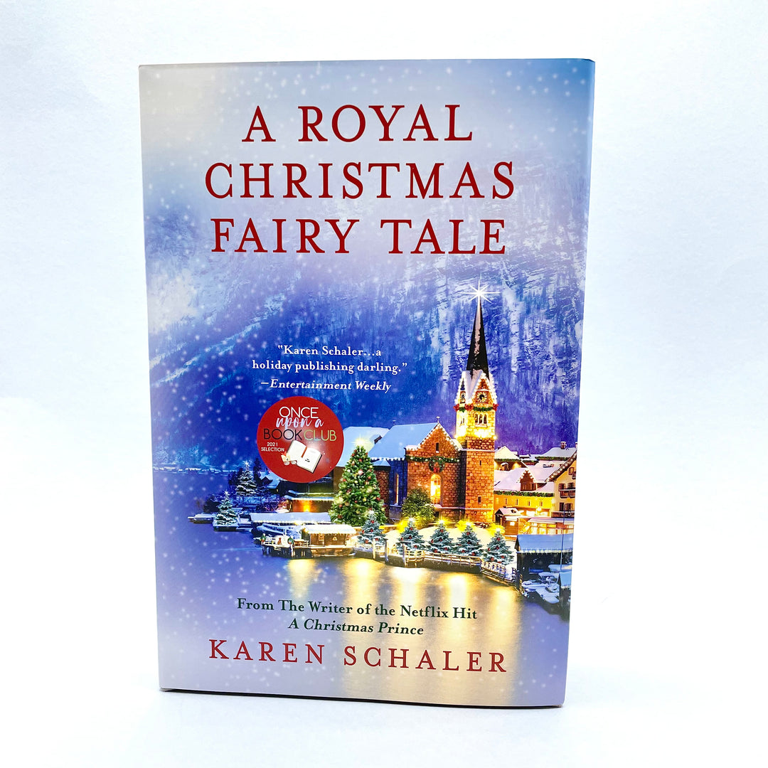 a hardcover edition of A Royal Christmas Fairy Tale by Karen Schaler. The cover shows a city at Christmas-time on the waters edge with a snowy mountain in the background