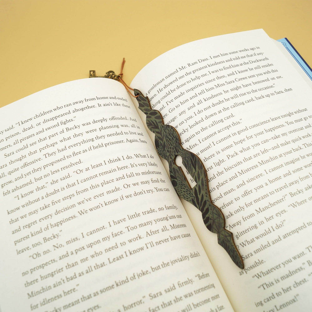 a black and dark green keyhole bookmark lays in an open book