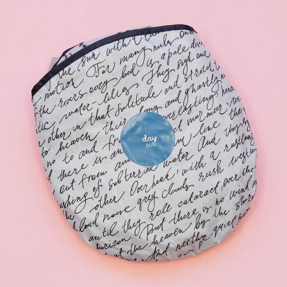 a circular bag containing a white sunshade with black script pattern across it