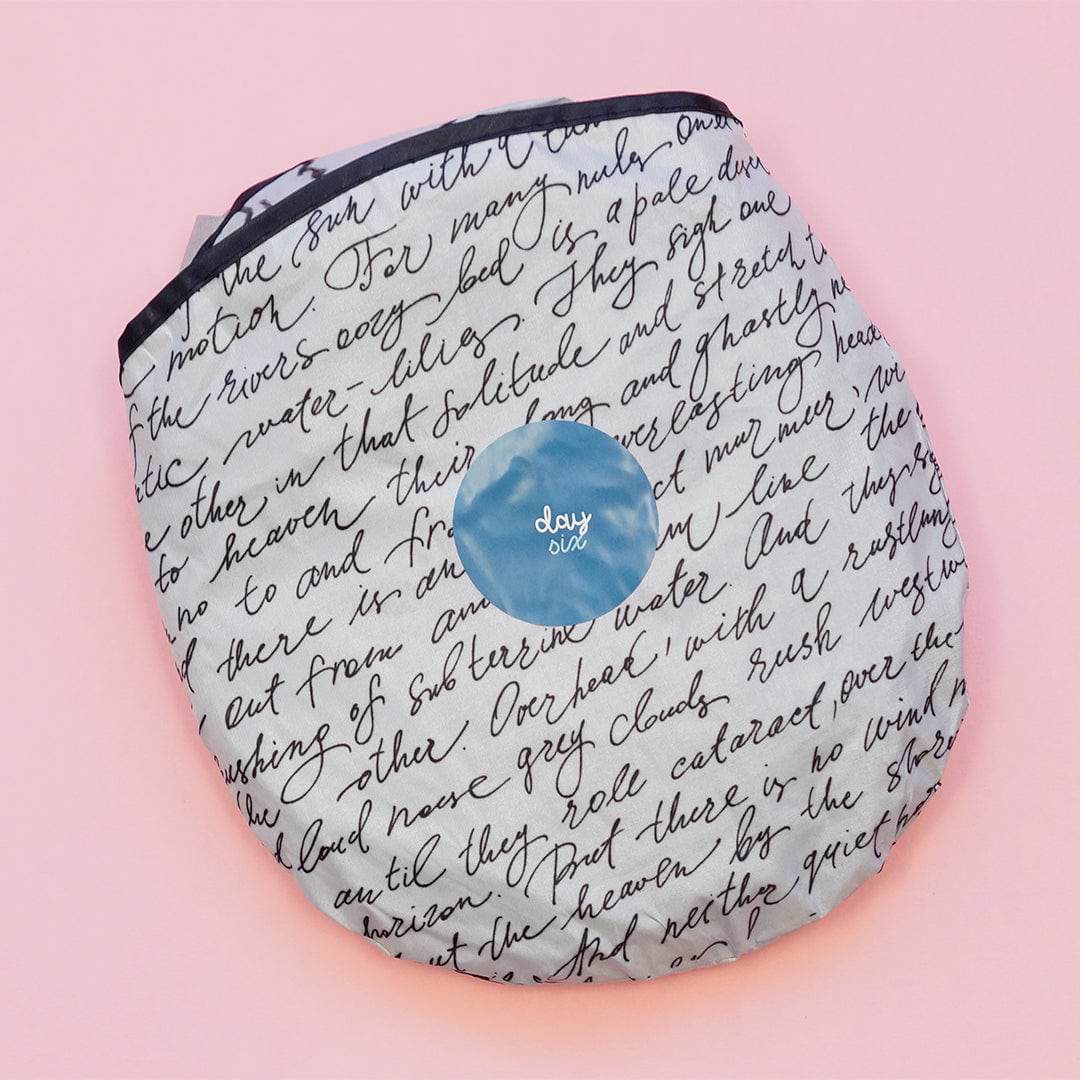 a circular bag containing a white sunshade with black script pattern across it