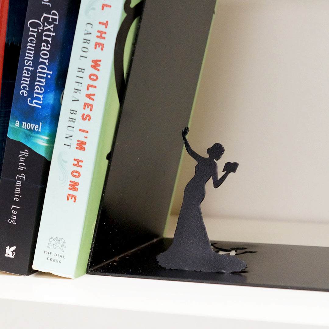 two paperback books are leaning against a black metal bookend of a woman reading a book and holding her other arm away from herself 