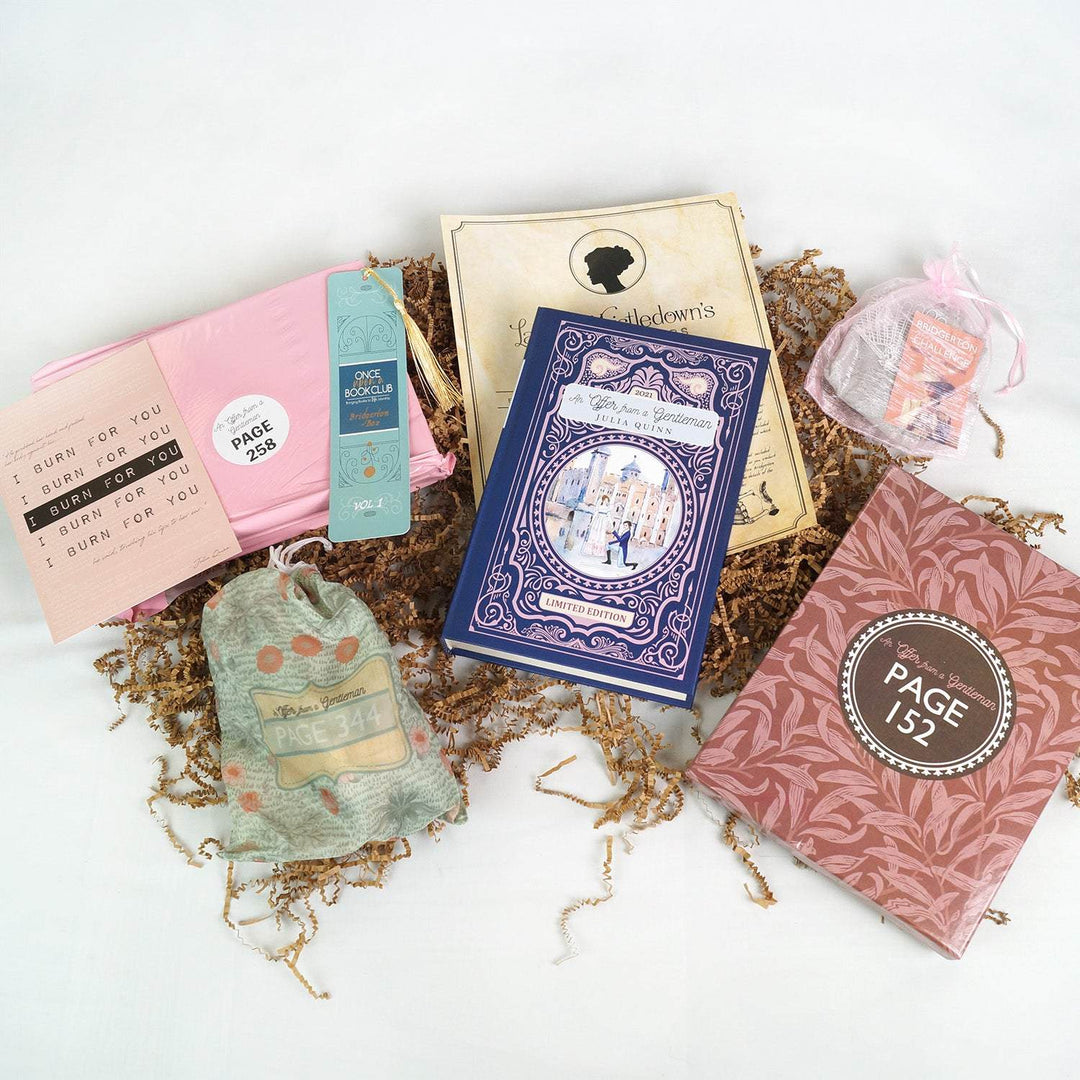 a blue hardcover special edition of An Offer From a Gentleman lays on a piece of beige paper. Surrounding the book are a quote card, pink polybag, bookmark with tassel, light green drawstring bag, pink drawstring bag, and red box. The boxes and bags are labeled with page numbers.