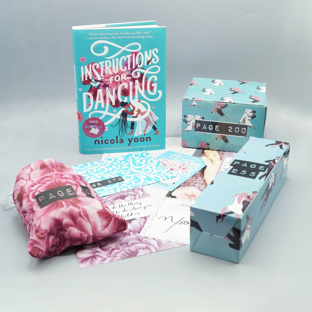 A hardcover edition of Instructions for Dancing stands next to a blue box. In front are a pink/red floral drawstring bag, blue and white envelope, pile of paper products, and blue rectangular box. The boxes and bags all have page numbers.