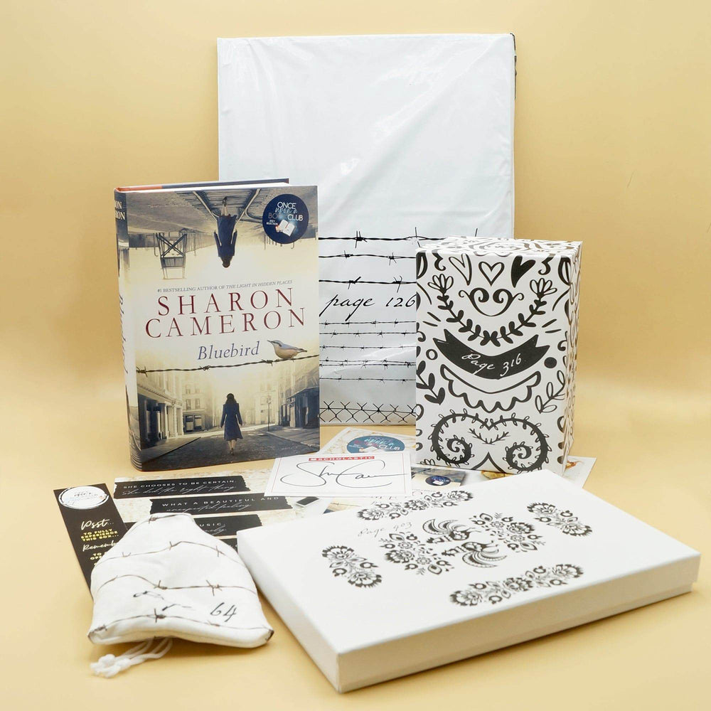 A hardcover edition of Bluebird stands next to a white polybag, two white and black boxes, white drawstring bag, and an assortment of paper items.