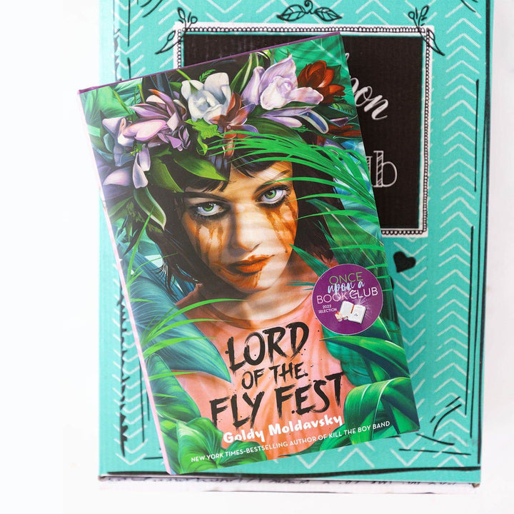 a hardcover edition of Lord of the Fly Fest lays on a green Once Upon a Book Club box
