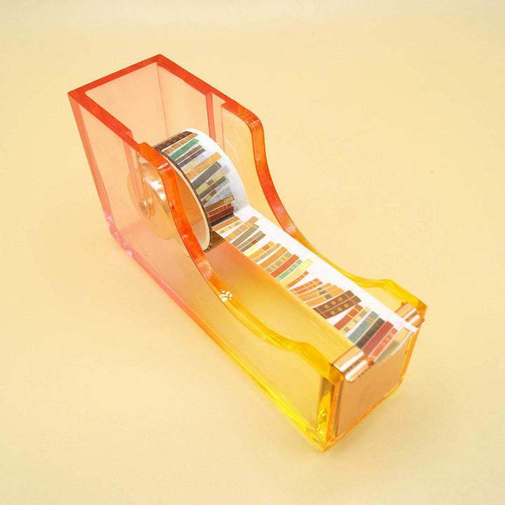a pink/yellow ombre tape dispenser with book-patterned washi tape