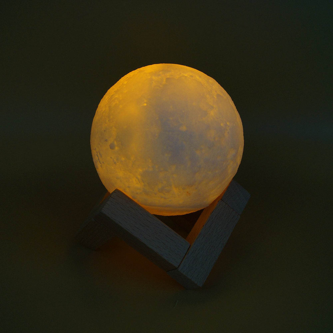 A moon light glowing peach/rose colored on a wooden stand