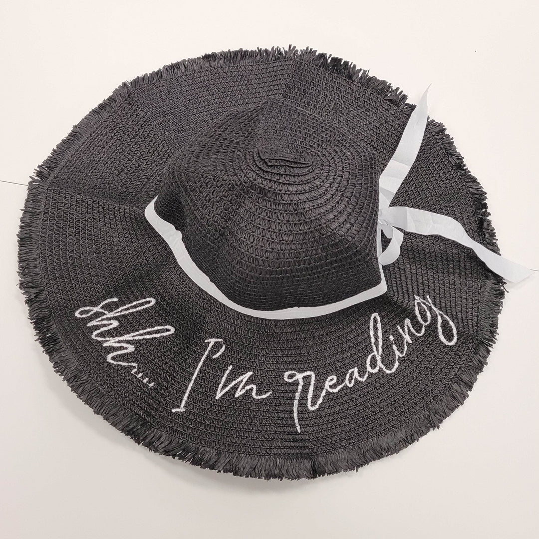 a black sunhat that has "Shh I'm Reading" embroidered in white