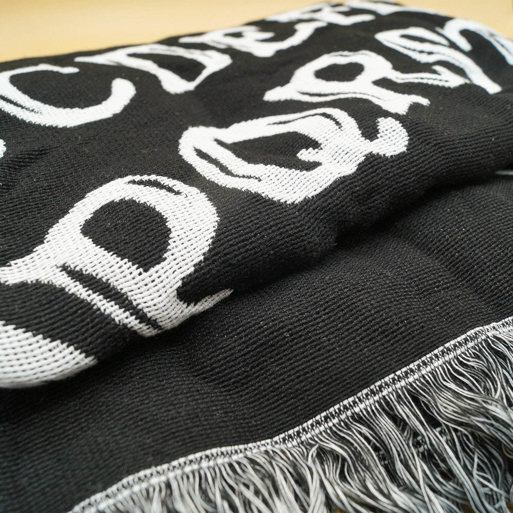 a black woven blanket folded up with black and white tassels