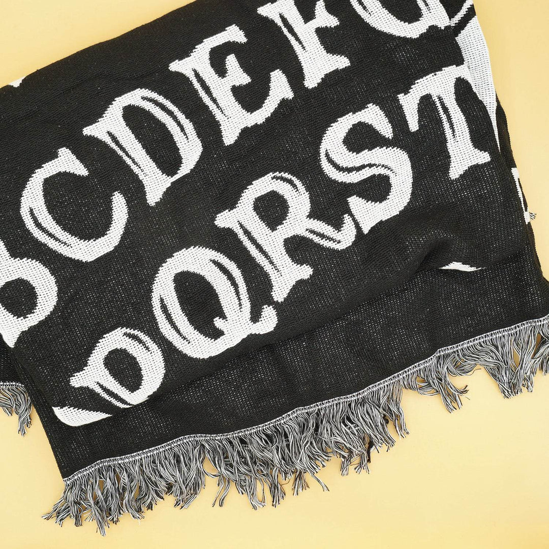 a black woven blanket folded up with white letters on it