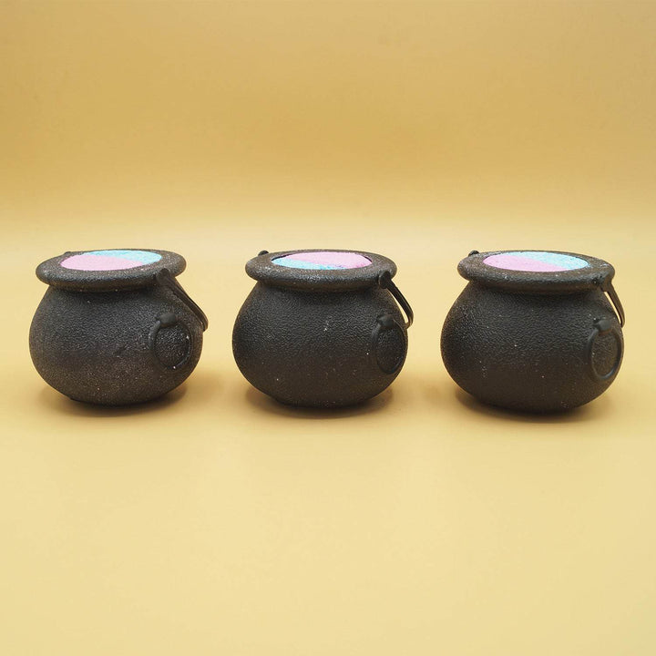 three black cauldron-shaped bath bombs stand in a line
