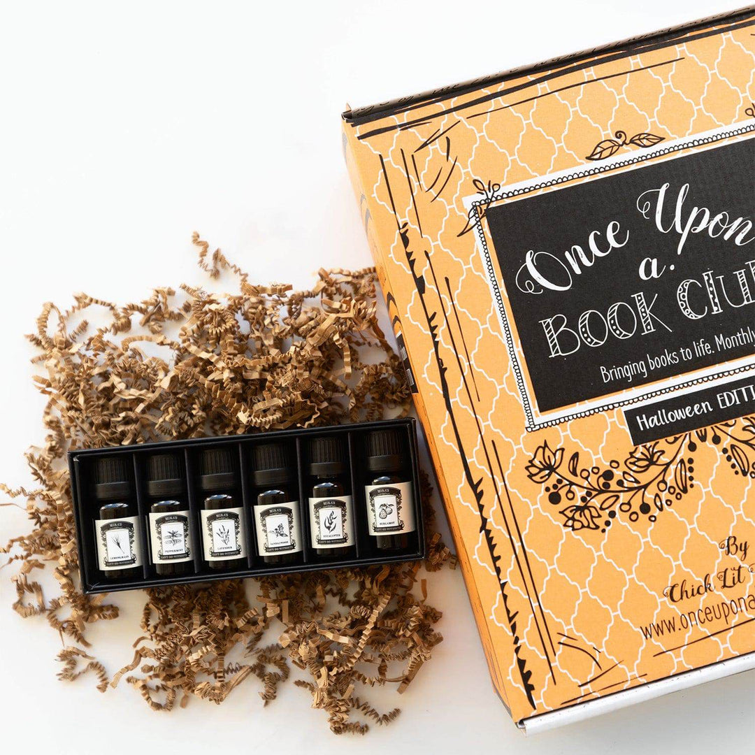 a box of six essential oils lays open next to an orange Once Upon a Book Club box