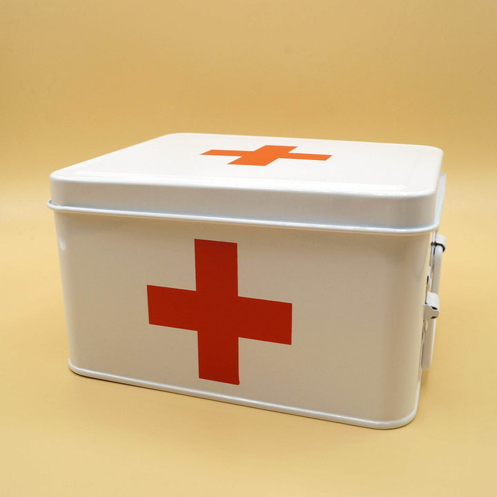 a closed white metal first aid box with a red cross on the front and top