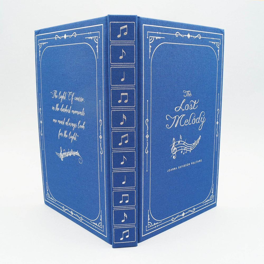 The hardcase of a special edition of The Lost Melody. The book is blue with silver writing and silver music notes down the spine