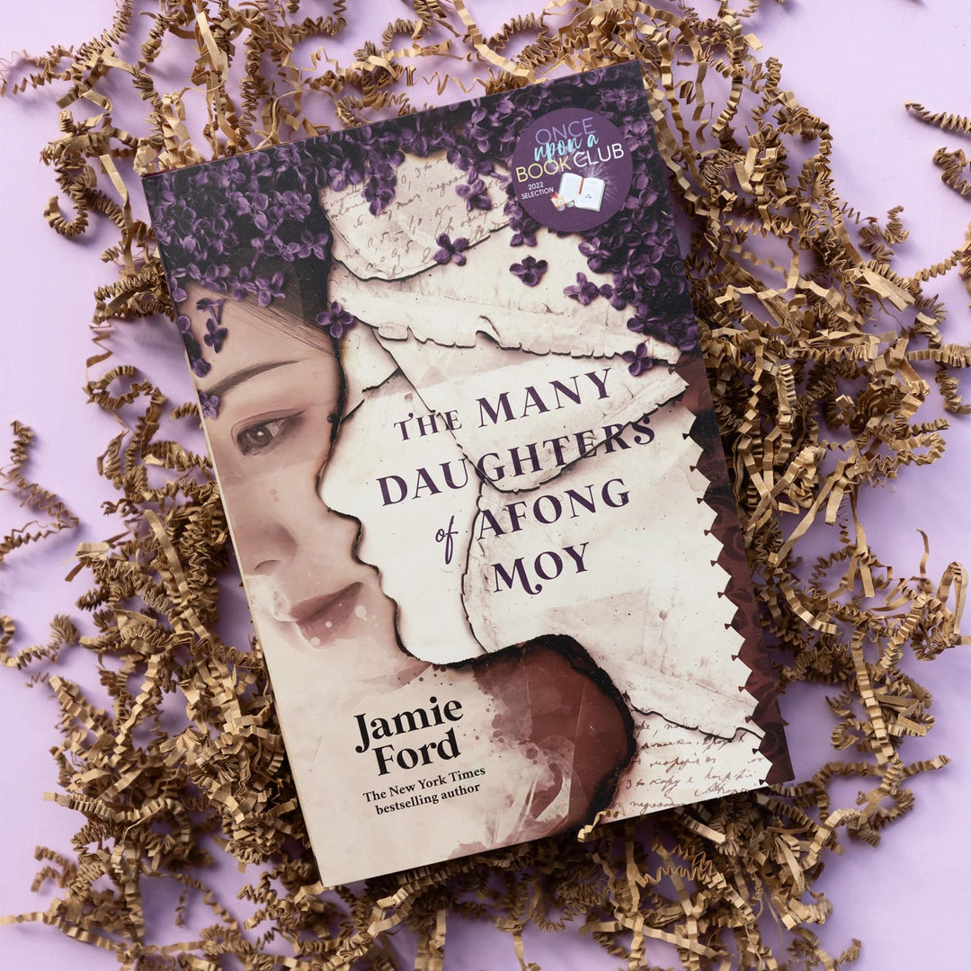a hardcover special edition of The Many Daughters of Afong Moy by Jamie Ford lays on brown crinkle paper