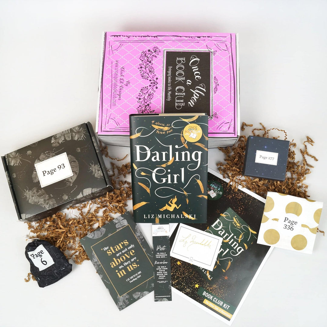 A hardcover edition of Darling Girl leans against a pink box. In front of the box are a black box, black drawstring bag, quote card, bookmark, signature card, bookclub kit, black box, and white and gold envelope. The boxes and envelope all have page numbers on them