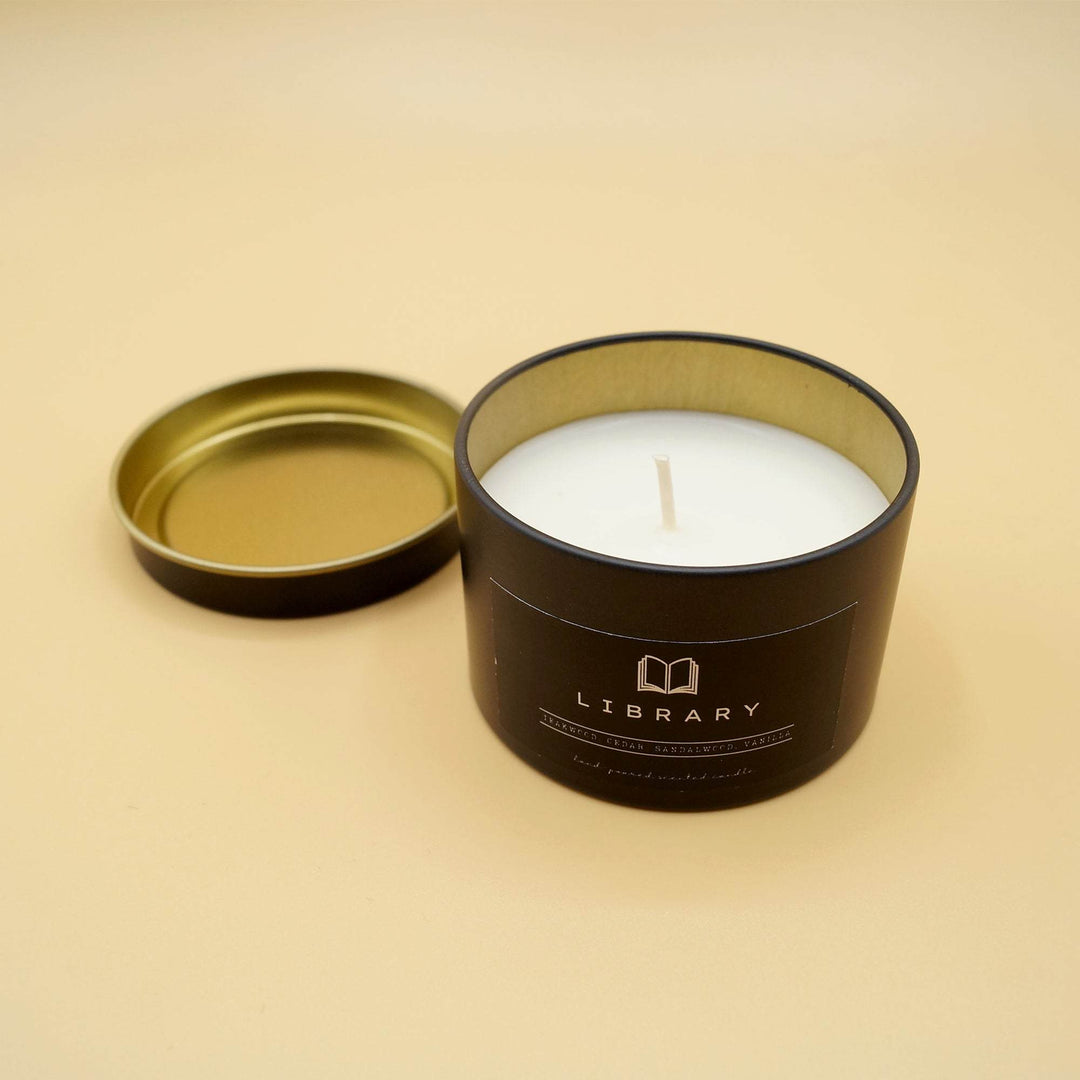 an open black candle labeled Library with the lid next to it