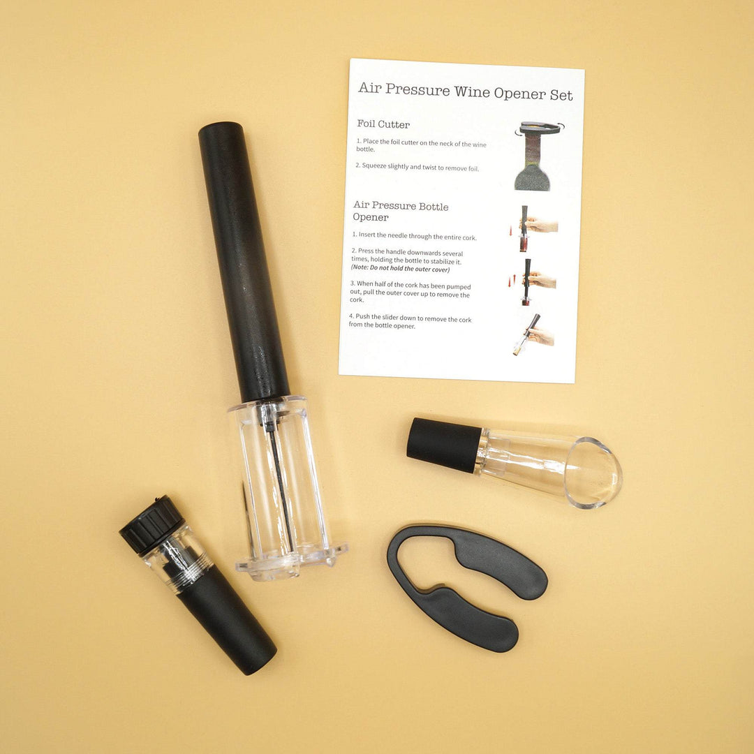 A set of black wine tools including an air pressure wine opener, a foil cutter, an aerating wine pourer, and a vacuum wine stopper along with an information card