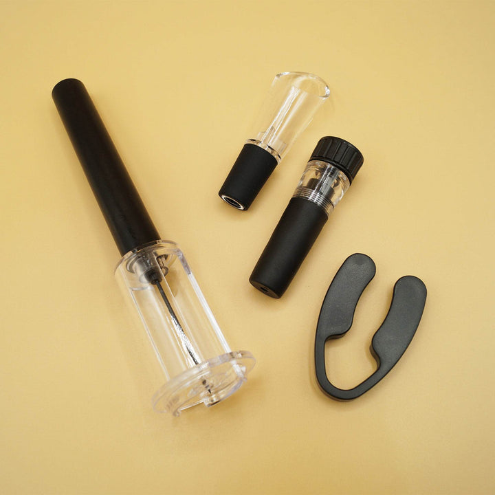 A set of black wine tools including an air pressure wine opener, a foil cutter, an aerating wine pourer, and a vacuum wine stopper