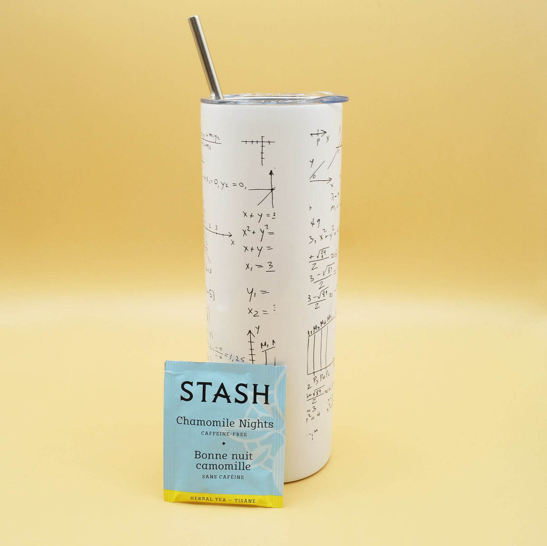 a white tumbler with black equations across it and a metal straw coming out of the top is next to a packet of Stash tea