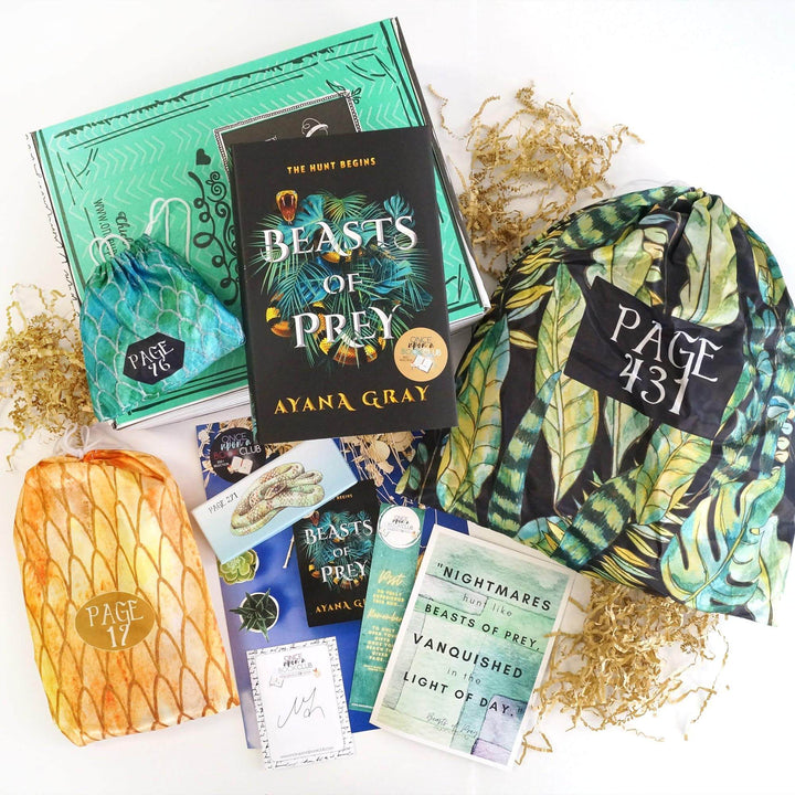 A hardcover edition of Beasts of Prey and a green drawstring bag are on top of a green Once Upon a Book Club box. In front of the box are a gold drawstring bag, small box with a snake on it, signature card, bookclub kit, bookmark, quote card, and back and green drawstring bag. The boxes and bags all have page numbers on them.
